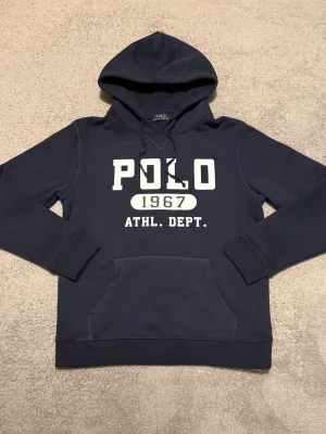 Ralph Lauren hoodie - Säljer en riktigt snygg hoodie från Ralph Lauren i ett mycket bra skick, som nytt. Storleken på etiketten säger XL, men den sitter som en M/L. Se mått: Total längd: ca 68cm, Bredd under armarna: ca 55cm. Hör av er vid frågor!😊