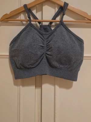 Blått sport-bh med brottarrygg - Mörkgrå sport-bh med brottarrygg och lätt rynkning framtill. Tillverkad i mjukt, stretchigt material som ger bra stöd. 