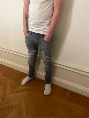 Slim fit ljusblå jeans herr - Snygga slim fit jeans i ljusblå denim med mörkare tvätt vid knän och vader. Klassisk femficksmodell med dragkedjegylf och smal passform. Perfekta för en trendig och avslappnad look.