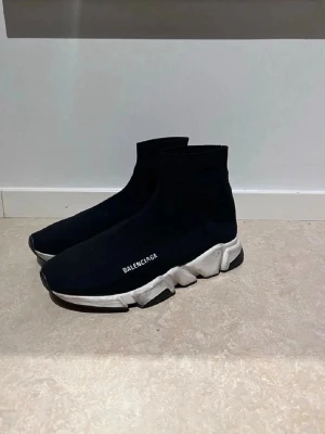 Svarta Balenciaga Speed sneakers - Säljer ett par svarta Balenciaga Speed sneakers med vit chunky sula och stickad ovandel som sitter som en strumpa. Loggan är tryckt i vitt på sidan. Skorna har en futuristisk vibe och är riktigt bekväma tack vare den elastiska textilen.