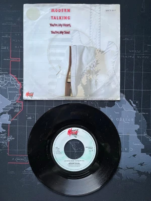 Modern Talking vinylsingel - Vinylsingel med Modern Talking, låten 'You're My Heart, You're My Soul'. Skivan är svart och omslaget är vitt med röd text och motiv av en vit sko. Perfekt för dig som gillar retro och samlar på klassisk popmusik.