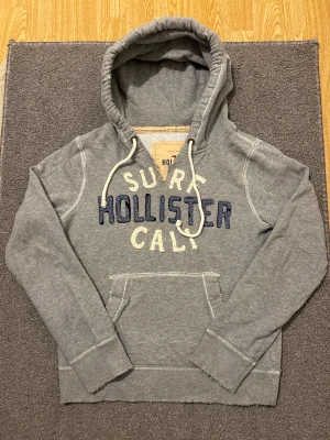 Vintage Hollister Hoodie - Extremt sällsynt och unik Hollister Hoodie med tryck | Hoodien har en unik sliten & distressed design! | Mycket bra skick, (misstänker dock att öppningen vid halsen är lite större än vad designen ska vara)| Storlek S | Längd≈ 65 cm, Bredd 55 cm under armhål-armhåla| Modell 175cm, 68kg | Priset ej hugget i sten! 