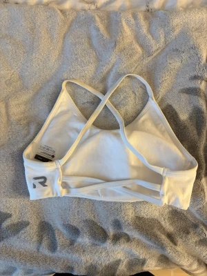 Vit sport-bh med korsade band - Säljer en vit sport-bh från Relode med tunna korsade axelband i ryggen. Bh:n är tillverkad i ett mjukt och stretchigt material som ger bra stöd och komfort. Enkel och stilren design💓säljer för att den är för liten för mig💓