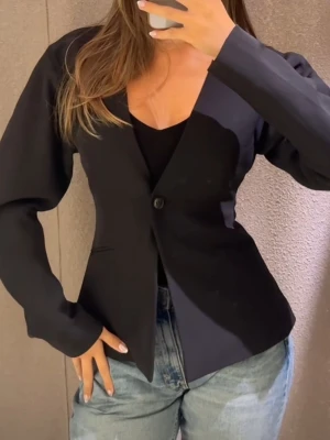 Svart SHAPED kavaj från Gina Tricot - Stilren svart kavaj från Gina Tricot med en knapp framtill och två fickor. Klassisk rak passform och djup V-ringning. Perfekt för att lyfta vilken outfit som helst. Materialet ser ut att vara en blandning av polyester och viskos. Storlek 40. Jag tycker att den är kanske lite mindre i storleken men kan mätas vid behov. Fõrsta bilden är inte min egna. 