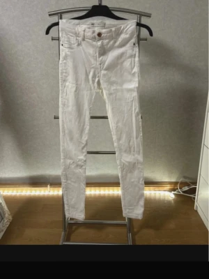 Vita Molly jeans från Gina Tricot - Säljer ett par vita Molly jeans från Gina Tricot. Jeansen är stretchiga och har en knapp i bronsfärg. Perfekta för en clean och fräsch look.