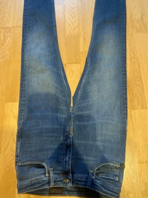 Blå raka jeans med fem fickor - Snygga blå jeans med klassisk rak passform och fem fickor. Jeansen har normal midja, dragkedjegylf och subtila slitningar för en avslappnad look. Tillverkade i denim med lätt stretch för extra komfort. Storlek 30/30 priset är ej hugget i sten