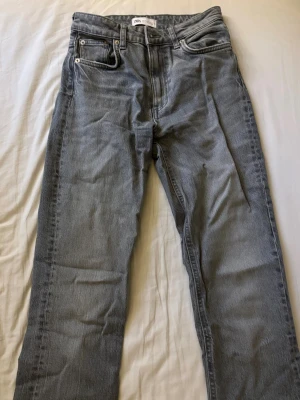 Grå utsvängda jeans från Zara med slit vid benen  - Säljer ett par grå jeans från Zara med rak passform och klassisk femficksdesign. Jeansen har normal midja och stängs med dragkedja och knapp. Perfekta för en avslappnad och trendig look. För fler bilder skriv gärna🩷