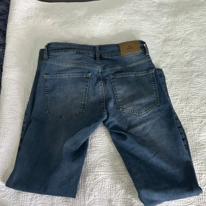 Blå bootcut jeans från Nelly - Snygga blå jeans från Nelly med bootcut-modell och låg midja. Jeansen har markerade sömmar längs benen, dubbla framfickor med dragkedjedetaljer och klassiska bakfickor. Perfekta för dig som gillar en retro vibe och vill ha något som sticker ut. Jag är inte säker men tror den är i storlek 36, den är iaf för 152 cm.