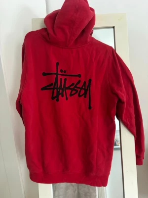 Röd hoodie från Stüssy - Snygg röd hoodie från Stüssy. Köpte på plick för ett tag sen men använt fåtal gånger. 
