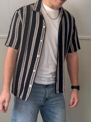 Svart kortärmad randig skjorta - Snygg svart skjorta med vita ränder och korta ärmar. Använd ett fåtal gånger