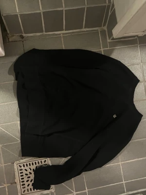 Svart sweatshirt med liten logga - En svart sweatshirt från Morris med rund hals och lång ärm. Tröjan har en liten broderad logga på bröstet och ribbade muddar vid ärmslut och nederkant. Perfekt för en clean och enkel stil.