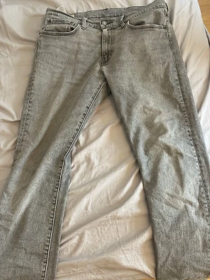 Grå Levi's 502 - Säljer ett par grå raka jeans från Levi's med klassisk femficksmodell och den ikoniska röda Levi's-lappen vid bakfickan. Jeansen har en snygg tvättad look och är tillverkade i slitstark denim. Perfekta för en avslappnad och trendig stil. Storlek 31/32