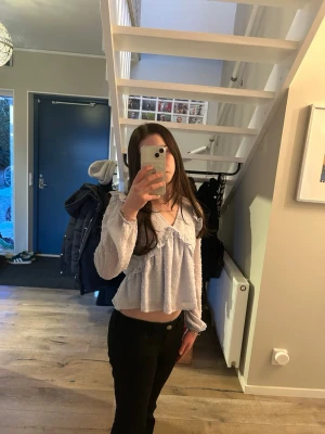 Ljusblå volangblus med prickar - Supersöt ljusblå blus med volangdetaljer och små prickar. Blusen har v-ringning, lång ärm med resår vid ärmslut och en luftig, lite croppad passform. Perfekt för en trendig och feminin look.