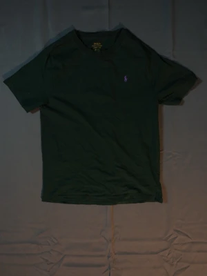 Svart t-shirt från Polo Ralph Lauren - Klassisk grönt-shirt från Polo Ralph Lauren med rund halsringning och korta ärmar. Diskret lila logga broderad på bröstet. Tillverkad i mjuk bomull som känns skön mot huden. Perfekt basplagg för en clean och stilren look.