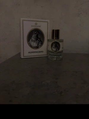 Zoologist Hummingbird parfym - Unik parfym från Zoologist med namnet Hummingbird. Flaskan är rund och genomskinlig med guldfärgat lock och elegant etikett med kolibri-motiv. Kommer i en vit och guld dekorativ box med samma illustration. Perfekt för dig som gillar exklusiva dofter.