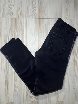 Svarta slim fit jeans från Lee - Snygga svarta slim fit jeans från Lee med klassisk femficksdesign och diskreta sömmar. jeansen sitter slim fit och byxorna är i storlek W30 L34