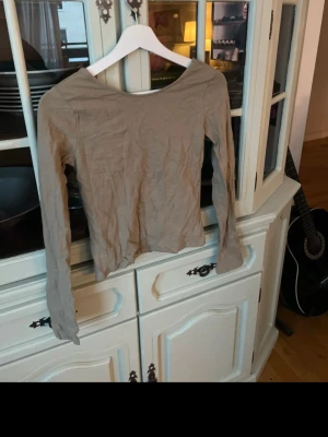 Olivgrön långärmad topp med djup rygg - Trendig olivgrön långärmad topp med rund halsringning fram och djup, öppen rygg. Tunn och mjuk i materialet.