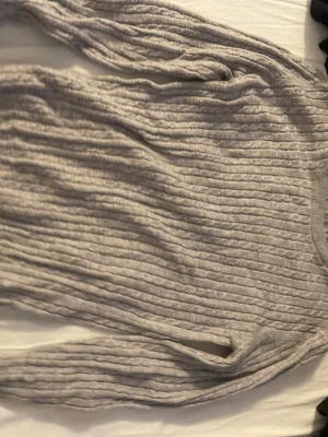 Grå kabelstickad tröja Gina Tricot - Säljer en grå kabelstickad tröja från Gina Tricot. Tröjan har rund halsringning, långa ärmar och ett klassiskt flätmönster över hela plagget. Perfekt för dig som gillar en enkel men snygg stil till hösten eller vintern.
