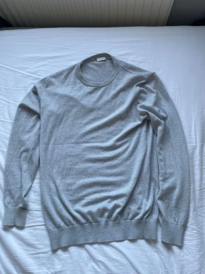 Ljusgrå stickad tröja från John Henric - En stilren ljusgrå tröja från John Henric med rund halsringning och långa ärmar. Tröjan har ribbade muddar vid ärmslut och nederkant, vilket ger en snygg passform. Stickad i 100% merinoull, storlek L. Pris går att diskuteras!