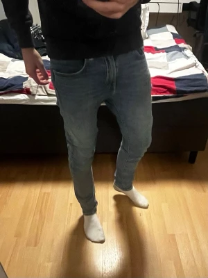 Blå slim fit jeans från Levi's - Säljer ett par klassiska blå slim fit jeans från Levi's med normalhög midja. Jeansen har en snygg tvättad look och är tillverkade i denim med stretch för extra komfort. Perfekta till vardags och passar till det mesta.