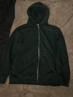 Mörkgrön oversized ziphoodie  - Snygg mörkgrön hoodie från Weekday med dragkedja framtill och stora fickor. Perfekt för en chill och avslappnad stil. Oversized i storleken