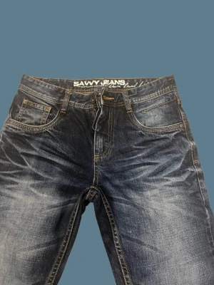 Mörkblå Savvy Jeans med slitningar - Säljer ett par mörkblå jeans från Savvy Jeans med snygga slitningar och tvättade detaljer. Storlek 28/32. 10/10 skick inga defekter. Tvättas innan fraktning!