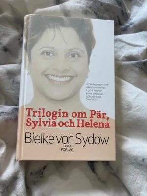 Trilogin om Pär, Sylvia och Helena - En samlingsvolym med tre romaner av Bielke von Sydow, utgiven av BIMA Förlag. Boken har ett stilrent omslag i vitt och beige med röd och svart text. Perfekt för dig som gillar svensk samtida skönlitteratur. Boken är signerade av henne och det står mitt namn i den.😊