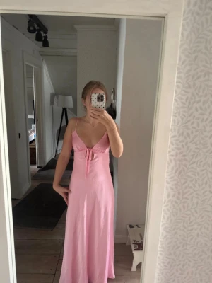 Rosa balklänning (xs) - Snygg rosa långklänning med knyt fram och även i rygg. Klänningen har en feminin passform och är ärmlös, perfekt för varma dagar. Mjuk och lätt i materialet, vilket gör den bekväm att bära. Klänningen är uppsydd så den passar på mig som är 160cm lång. Priset kommer inte sänkas då jag köpte den för 1200kr. Skriv vid frågor💞