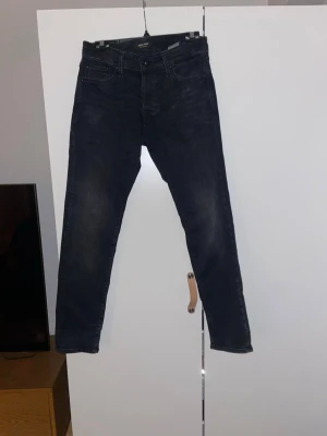 Svarta Jack & Jones jeans  - Ett par jeans från Jack & Jones som är väldigt prisvärda och populära. De är slim dessutom och sitter riktigt bra.  Har växt fram under senaste åren och ett måste att ha i sin gardenrob! Helt utan defekter! Hör av dig för fler bilder!