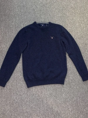 Mörkblå stickad tröja Gant - Mörkblå stickad tröja från Gant.                 OBS: BARN STORLEK M, men den har blivit mindre i tvätten, så den passar i BARNSTORLEK S. Knappt använd, som helt ny. 