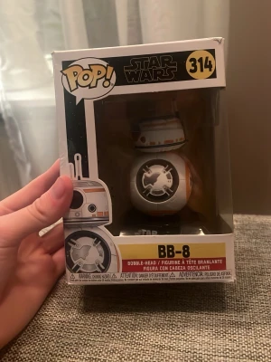 Funko Pop Star Wars BB-8 figur - Säljer en Funko Pop figur av BB-8 från Star Wars, nummer 314. Figuren är vit och orange med svarta detaljer och kommer i originalförpackning med fönster. Perfekt för samlare eller Star Wars-fans. Haft den stående i många år.