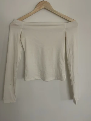 Vit offshoulder topp - Stilren vit långärmad offshoulder topp. Toppen har en enkel, tajt passform och är tillverkad i ett mjukt material. Perfekt för dig som gillar en trendig stil❣️