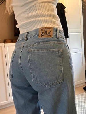 Blåa loose fit jeans Sweet Skateboarding - Säljer ett par ljusblå jeans från Sweet Skateboarding Company. Jeansen har en loose fit-modell med raka ben och klassiska bakfickor. De är tillverkade i denim och har en snygg patch med logga bak i midjan. Perfekta för en avslappnad streetstil.