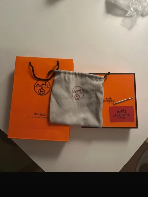 Svart  bälte med H-spänne - Snyggt svart bälte med ikoniskt H-spänne i silverfärgad metall. Bältet är i skinn och levereras med originalpåse, ask och påse. Perfekt accessoar för att lyfta din outfit.