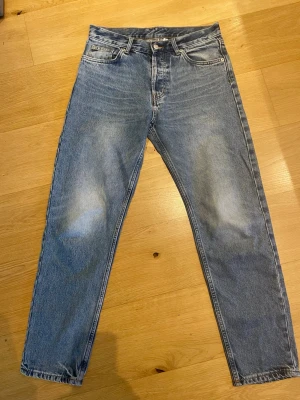 Jeans Weekday Barrel - Säljer ett par Weekday Barrel med rak passform och fem fickor. Jeansen har en klassisk ljus tvätt och är tillverkade i denim. Storlek W29, L32. Perfekta för en avslappnad och tidlös stil. Stängs med knapp och dragkedja framtill.