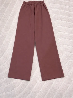 Vinrosa vida kostymbyxor  - Säljer ett par kostymbyxor med breda ben och resår i midjan. Byxorna har en avslappnad passform och är perfekta för en chill stil. Materialet känns mjukt och bekvämt, 