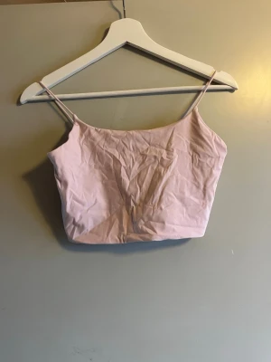 Ljusrosa linnetopp från Garage - Supersöt ljusrosa linnetopp från Garage med tunna axelband och enkel, croppad passform. Perfekt att styla med jeans eller kjol för en chill look. Mjuk och skön känsla tack vare bomullsmaterialet.