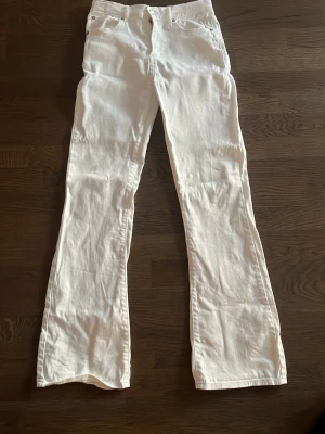 Vita bootcut jeans med fem fickor - Säljer ett par vita bootcut jeans med klassisk femficksmodell och normal midja. Jeansen har en snygg utsvängd passform och är perfekta för dig som vill ha en clean och fräsch look. Materialet är kraftigt denim i bomull. Passar till många olika stilar!