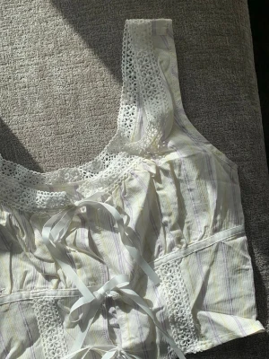 Sommarromantiskt linne med spets och rosetter - Supersöt topp, dekorerad med spets och snöre som knyts till rosetter. Perfekt för en romantisk och trendig look. Summerlove 💐💐💐