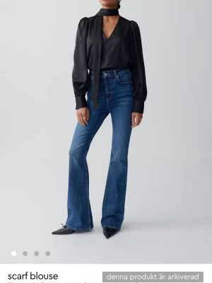 SÖKER!!!!!Svart scarfblus med puffärm - Stilren svart blus med lång ärm och puffiga axlar. Blusen har en dekorativ scarfdetalj vid halsen som kan knytas på olika sätt. Tillverkad i ett glansigt, mjukt material som ger en lyxig känsla. Perfekt för att lyfta vilken outfit som helst.