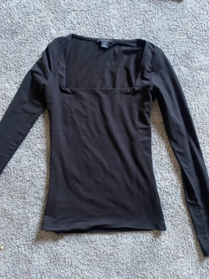 Svart långärmad topp  - En stilren svart långärmad topp med fyrkantig halsringning. Toppen är figurnära och gjord i mjukt bomullsmaterial, perfekt för att skapa en clean och modern look. Endast provad💗
