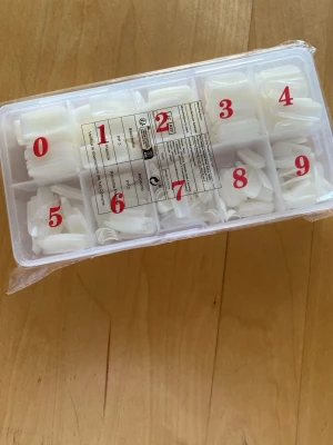 Vita press-on naglar i olika storlekar - Säljer ett set med vita press-on naglar i tio olika storlekar, perfekt för att fixa snygga naglar snabbt hemma. Naglarna har en naturlig form och kommer i en praktisk plastlåda med fack för varje storlek. Materialet är tålig plast som är lätt att fila och forma.