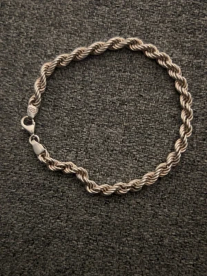 Tvinnat silverfärgat armband - Snyggt armband i tvinnad design med silverfärg. Armbandet har en klassisk karbinhake och är gjort av metall. Perfekt för dig som gillar stilrena accessoarer med lite extra detalj.