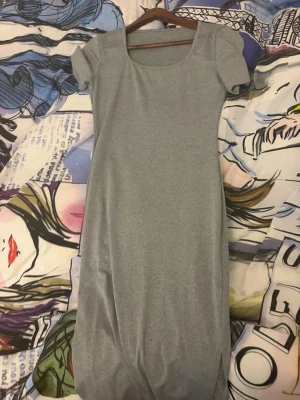 Grå kortärmad klänning - En enkel och stilren grå klänning med korta ärmar och rund halsringning. Klänningen har en rak passform och är tillverkad i ett mjukt material som känns bekvämt mot huden. Perfekt för en avslappnad look