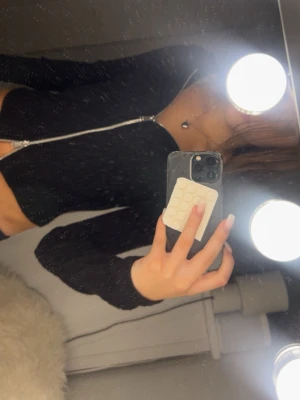 Svart ribbad zip-kofta - Svart ribbad kofta med dubbel dragkedja framtill och långärmad design. Koftan har en figurnära passform och är tillverkad i ett stretchigt material som ger en snygg siluett. Perfekt för att skapa en cool och enkel look.