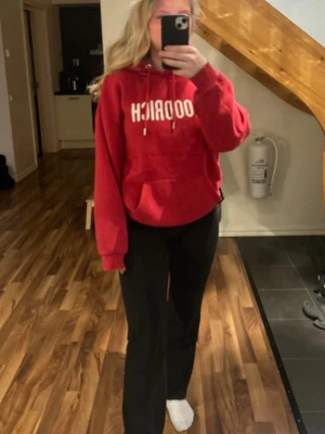 Röd hoodie från HOODRICH - Säljer en röd hoodie från HOODRICH med vit logotyp på bröstet. Hoodien har en stor ficka framtill,  justerbar huva med snören. Perfekt för dig som gillar en avslappnad och cool stil.