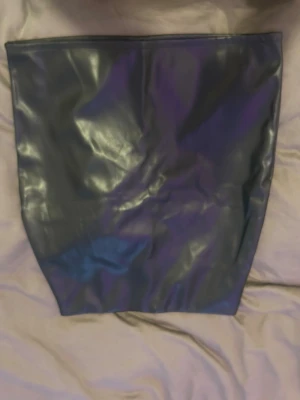 Svart tjol i fejkläder - Svart läderkjol, hamnar precis över knäna. Kramar till dina former perfekt då den är sydd på så sätt, passande för er clubtjejor!! Storleken är M men passar även mig som bär S