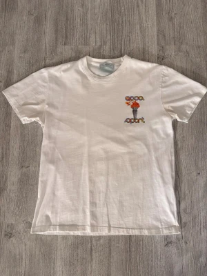 Vit Coca Sport t-shirt med tryck - Vit t-shirt från Coca Sport med färgglatt tryck av en fackla och texten 'coca sport' på både bröstet och ryggen. Klassisk rund hals och korta ärmar. Tillverkad i mjuk bomull för en skön och avslappnad stil.