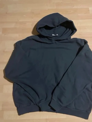 Svart hoodie från Acne Studios - Cool svart hoodie från Acne Studios med stor huva och tryck på ryggen: 'Acne Studios STOCKHOLM 1996'. Mjuk bomullskänsla och ribbade muddar vid ärmslut och nederkant. Perfekt för dig som gillar stilrena och trendiga plagg.