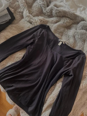 Svart långärmad topp från H&M - Svart långärmad topp från H&M med diskret ringning. Toppens material känns mjukt och stretchigt, perfekt för en stilren och enkel look. Passformen är figurnära. Perfekt basplagg 